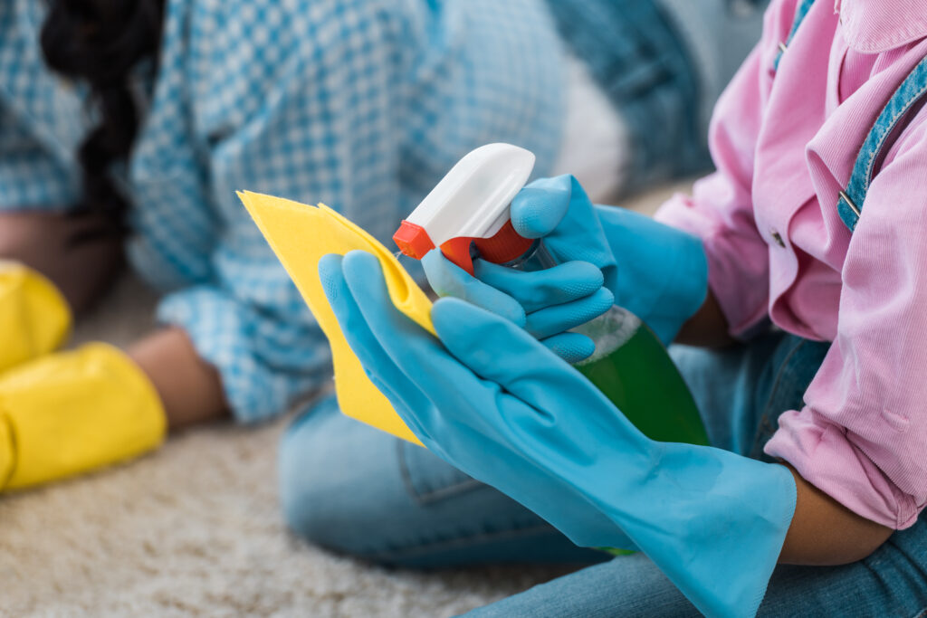 Cropped view of an African American child spraying cleaner, illustrating the health benefits of carpet cleaning by reducing allergens, dust, and improving indoor air quality.