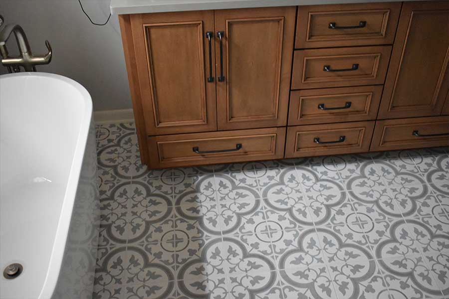 Elegant bathroom showcasing a tile and grout cleaning service with ornate gray and white patterned floor tiles, complemented by a wooden vanity with multiple drawers