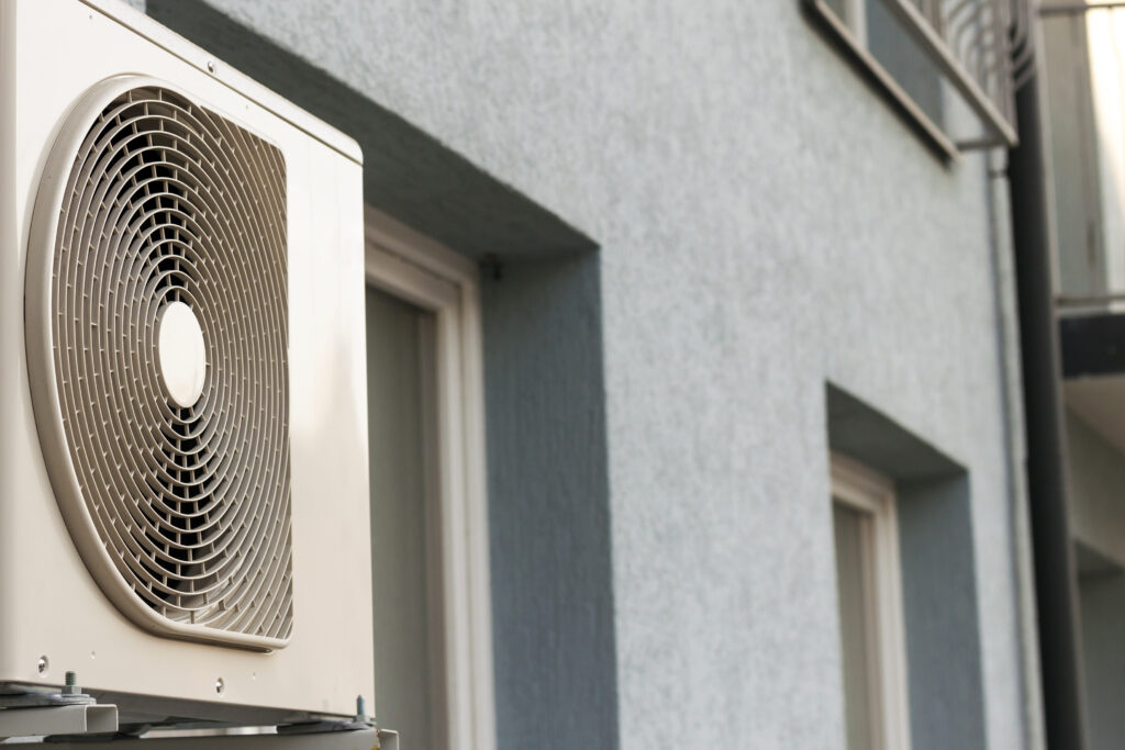 An outdoor unit of a split air conditioner installed on the wall of an apartment building, potentially linked to what causes mold in air ducts due to moisture and lack of maintenance.