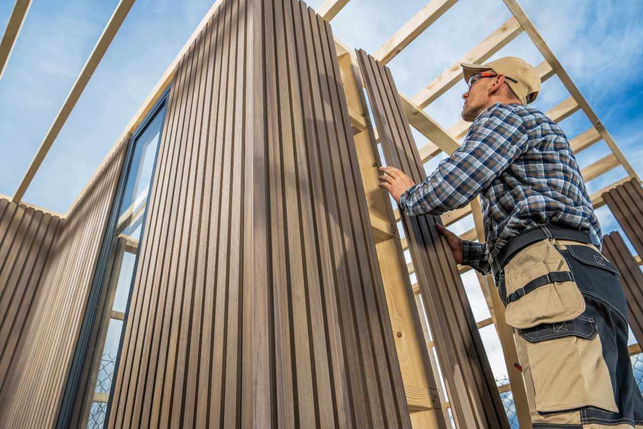 construction worker installing wooden siding to new construction home