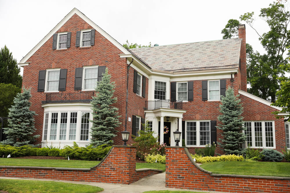 Elegant brick house with black shutters, demonstrating brick siding as a classic choice among different kinds of siding.