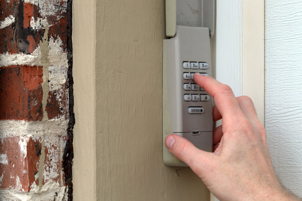 Hand pressing numbers on a garage door keypad. Malfunctioning keypads are a frequent issue among common garage door problems, often requiring replacement or repair.