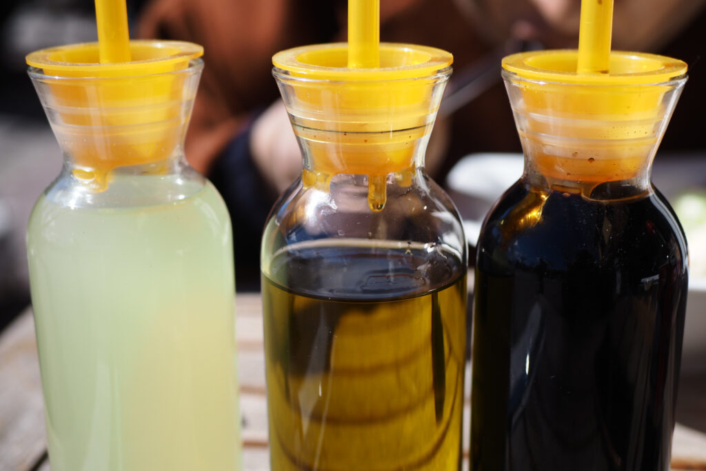 A bottle of vinegar, highlighted as an effective natural cleaner and one of the best ways to clean grout, paired with a soy sauce bottle on a countertop.