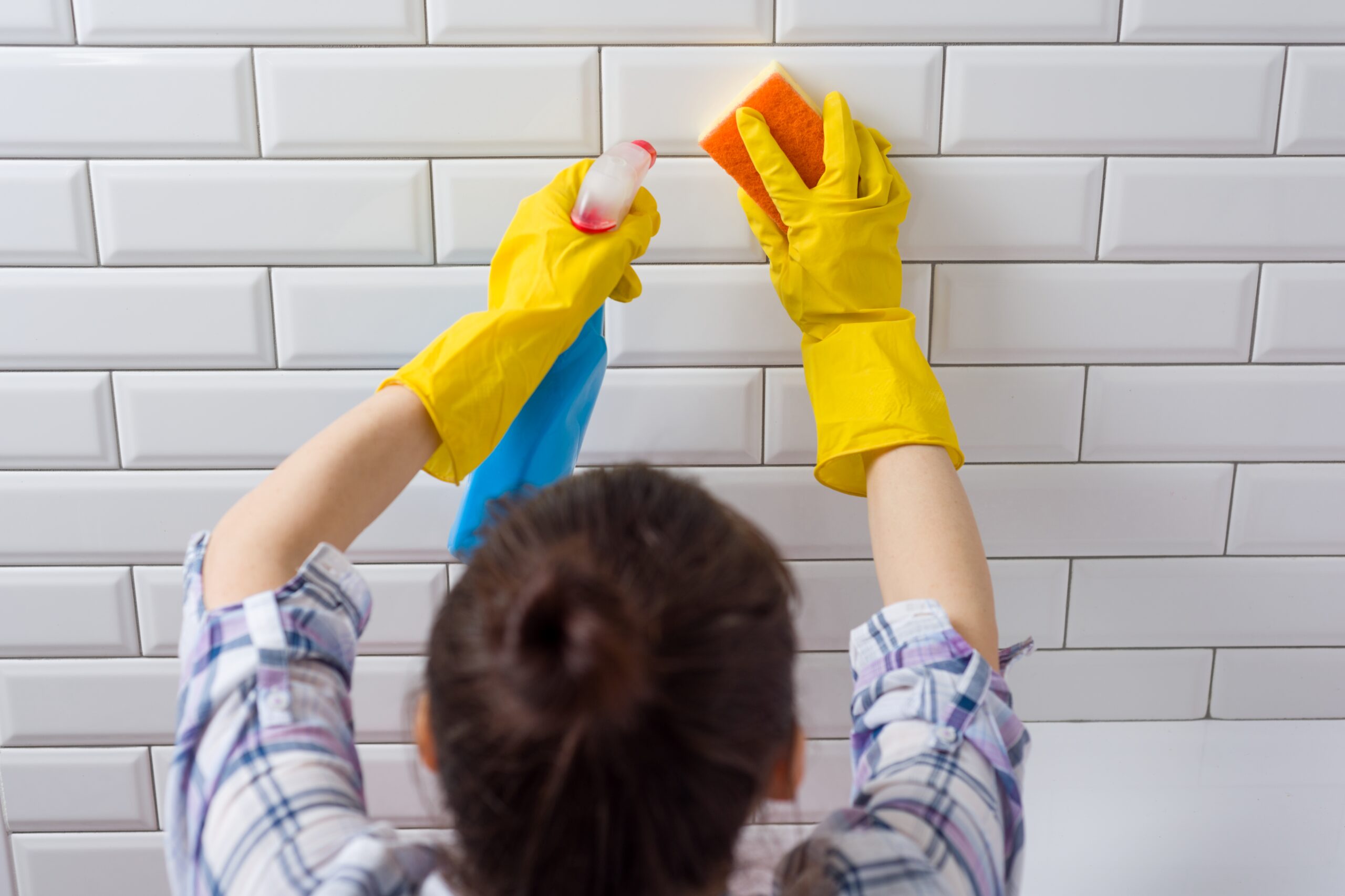 A woman using wipes to scrub bathroom tiles, showcasing the best way to clean grout effectively and keep surfaces sparkling.