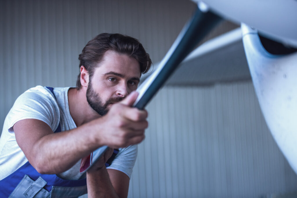 Repairman in blue uniform installing a new garage door, demonstrating replacement costs. Find out how much garage door repair or installation costs in detail.