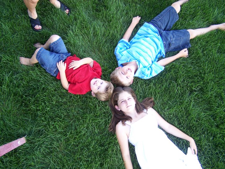 Children relaxing together on a healthy green lawn